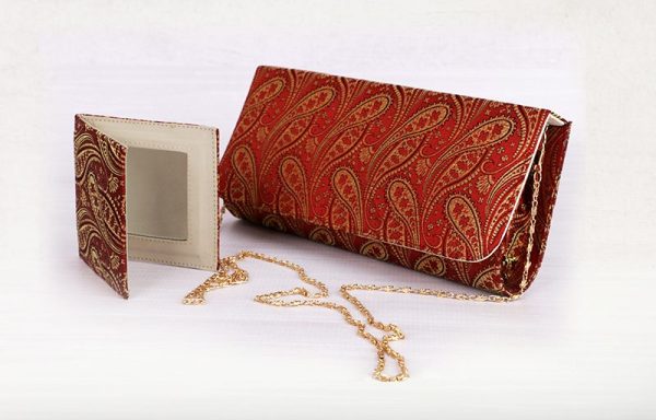 a red and gold brocade clutch purse with a matching mirror