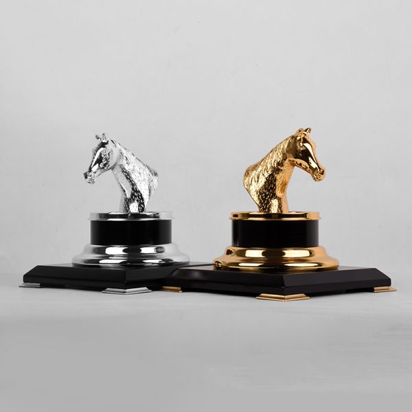 a silver or gold-plated brass horse head trophy on a black and gold base, symbolizing achievement and elegance